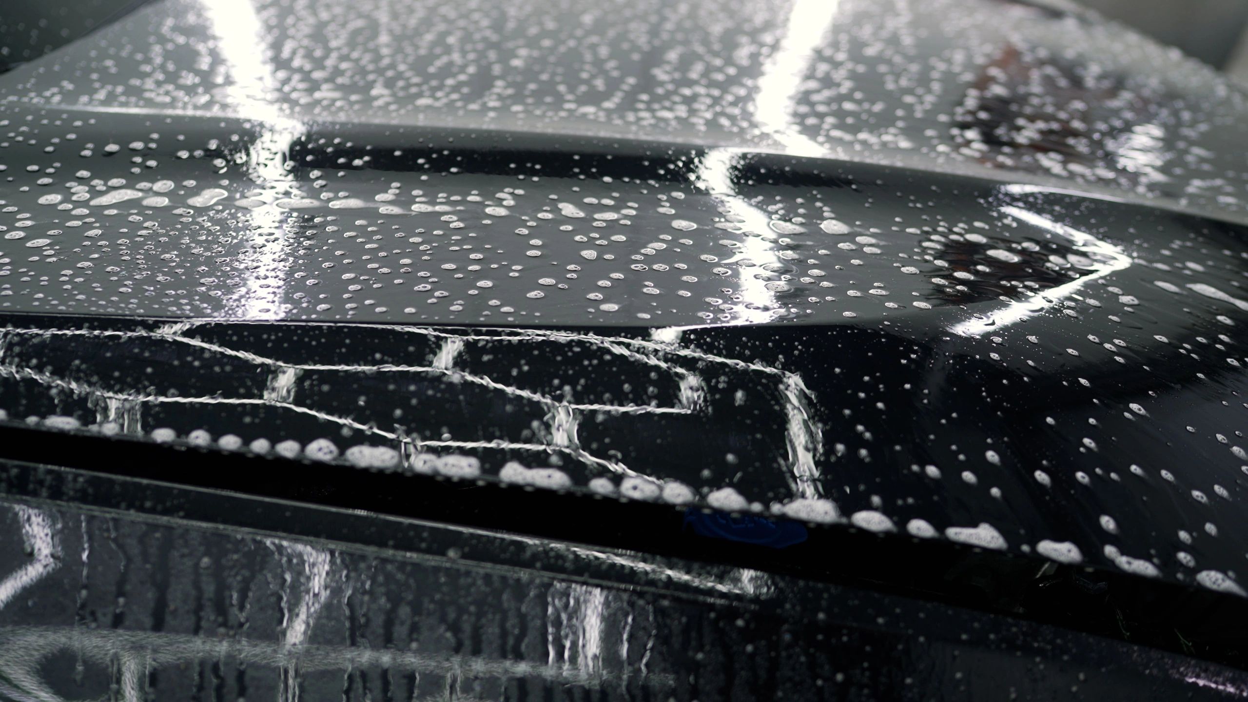 Detailer applying foam soap to a car hood during an exterior wash